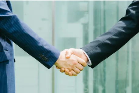 条件合意 → 契約・引き渡しのイメージ写真。スーツ姿の人物二人が握手をしている。