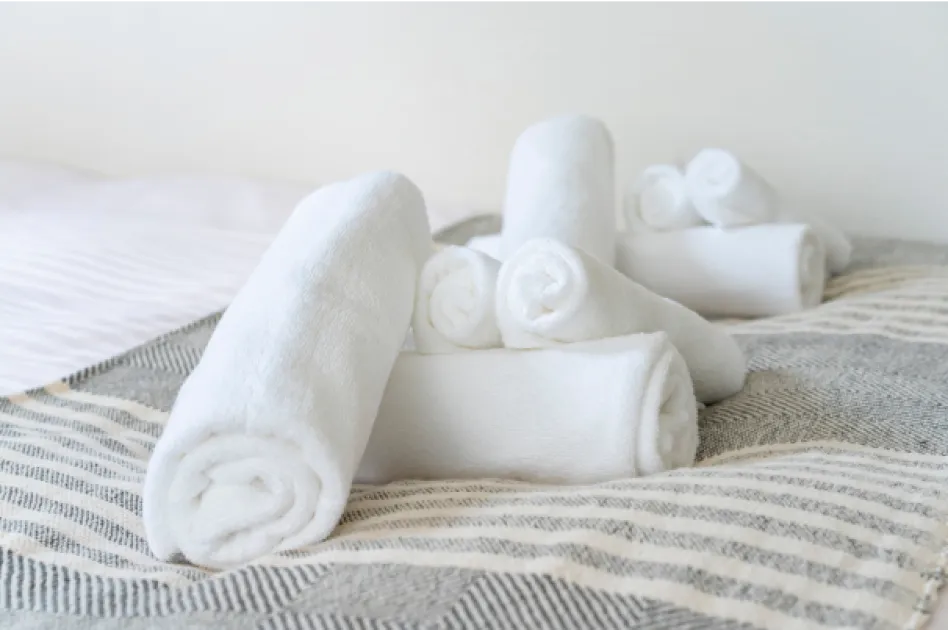 清掃契約や運営ノウハウなど営業の仕組みごと引き継げるイメージの写真。巻かれたタオルがベッドの上に複数置いてある。