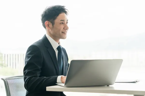 大手商社出身×M&A業界経験の担当者が直接対応するイメージの写真。スーツを着た男性がジェスチャーを交えて顧客に説明をしている。