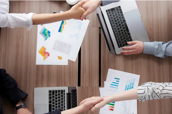 最短3日でのスピード成約のイメージ写真。デスクに資料やPCを広げて話し合い、握手を交わしている。